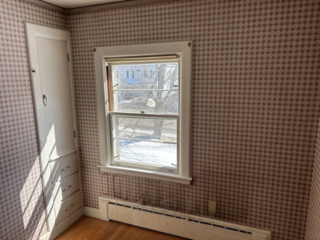 interior space featuring wallpapered walls, a baseboard heating unit, and light wood-style floors