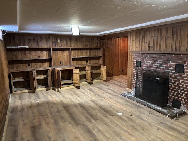 living area featuring light wood-style floors, a fireplace, and wood walls