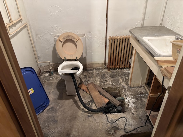 bathroom featuring radiator, a textured wall, toilet, vanity, and concrete floors