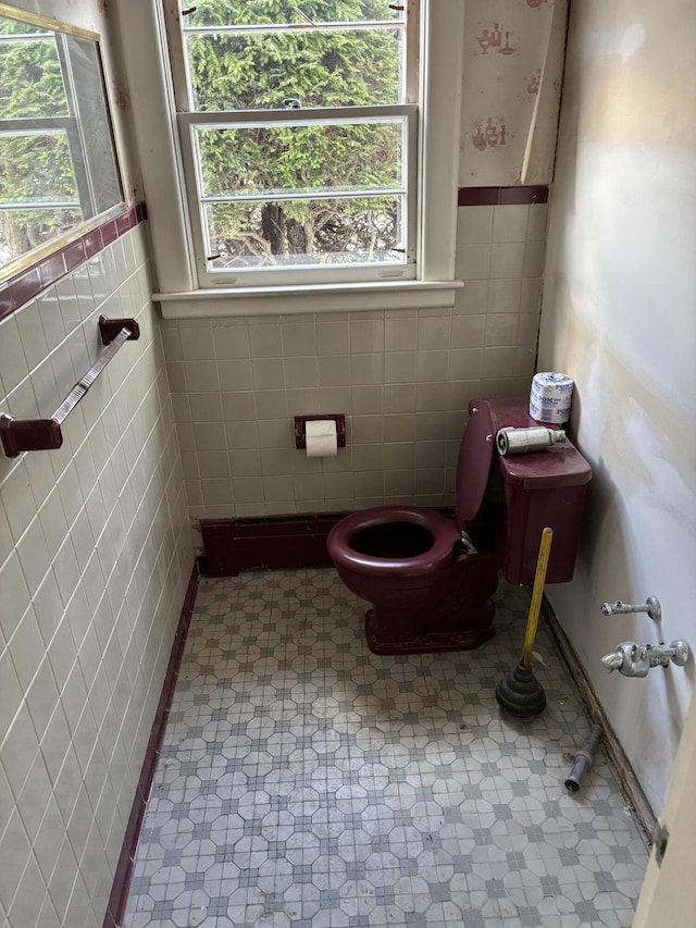 bathroom featuring a wealth of natural light, a wainscoted wall, toilet, and tile patterned floors