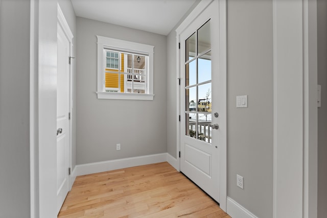 doorway to outside featuring baseboards, light wood-type flooring, and a healthy amount of sunlight