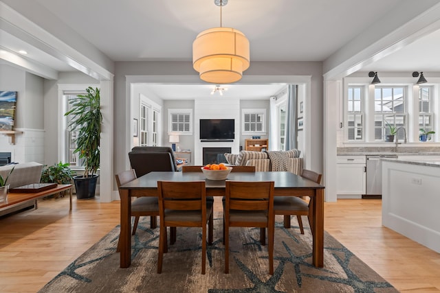 dining space with light wood-type flooring and a fireplace