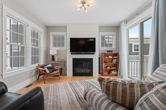 living area with baseboards, visible vents, a fireplace, and light wood finished floors