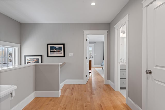 hall featuring light wood-type flooring and baseboards