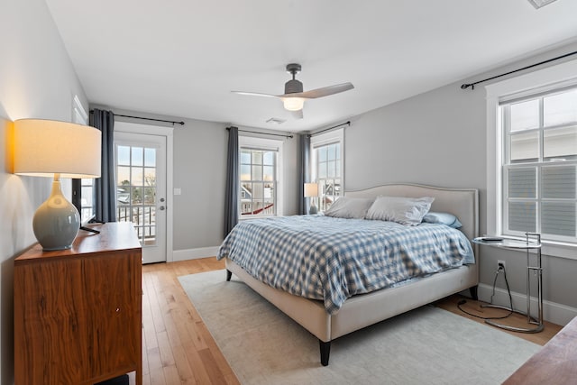 bedroom featuring baseboards, multiple windows, light wood-type flooring, and access to exterior