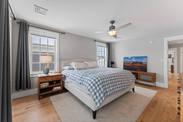 bedroom with light wood-style flooring, a ceiling fan, visible vents, and baseboards