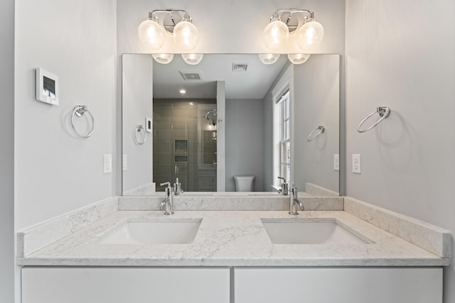 bathroom with double vanity, a stall shower, a sink, and toilet