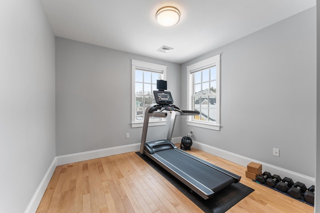 workout area with baseboards, visible vents, and wood finished floors