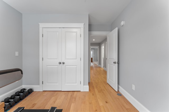 exercise room featuring baseboards and light wood-style floors