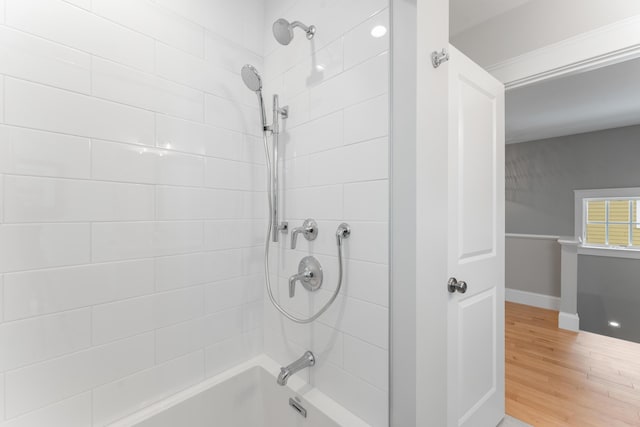 bathroom with bathtub / shower combination, baseboards, and wood finished floors