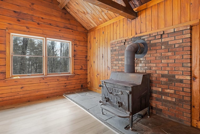 room details with a wood stove, wood walls, and beamed ceiling