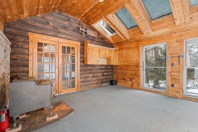 unfurnished living room featuring vaulted ceiling with skylight, french doors, rustic walls, and carpet