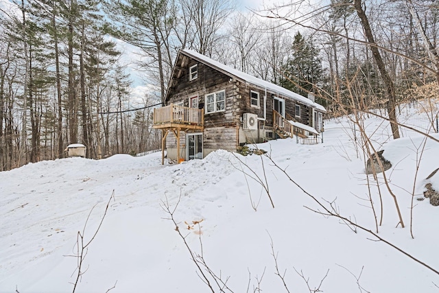 view of snowy exterior with a deck and log exterior