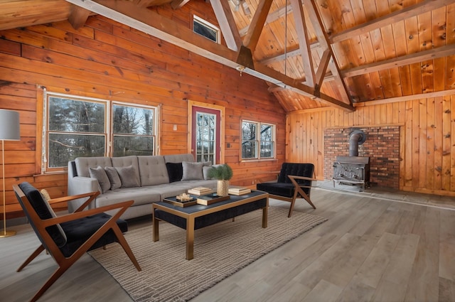 living area with wooden ceiling, wood finished floors, a wood stove, vaulted ceiling with beams, and wood walls