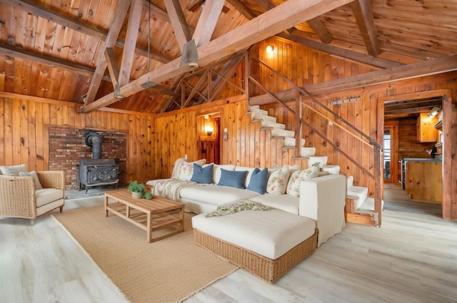 living area with stairway, wood ceiling, a wood stove, wooden walls, and wood finished floors