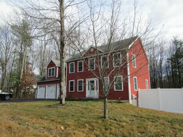 colonial house with aphalt driveway, a front yard, fence, and an attached garage