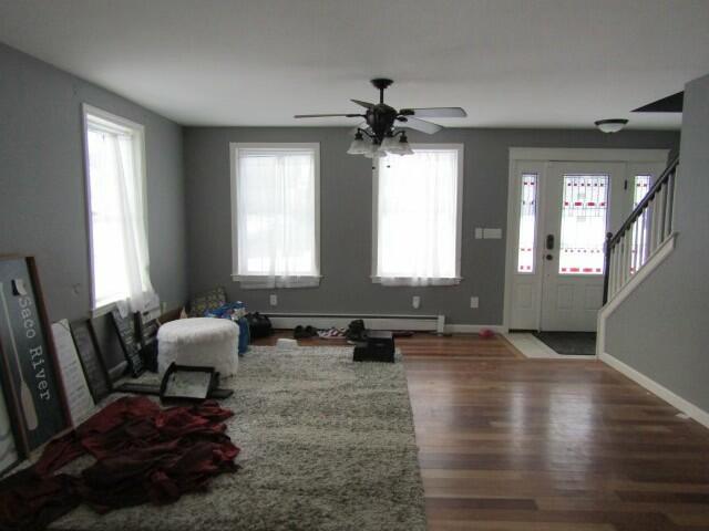 entryway with baseboards, ceiling fan, stairway, wood finished floors, and a baseboard heating unit