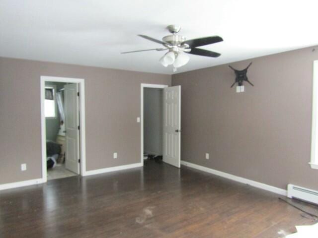 interior space with dark wood-style flooring, a ceiling fan, and baseboards