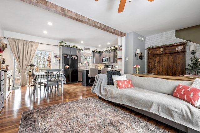 living room with dark wood-style floors, ceiling fan, brick wall, and recessed lighting