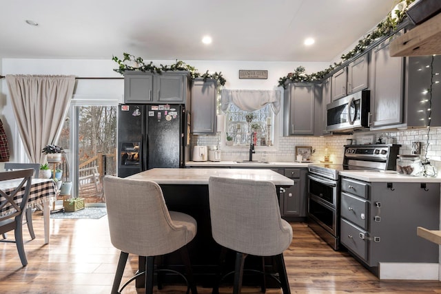 kitchen with gray cabinets, stainless steel appliances, light countertops, and a center island