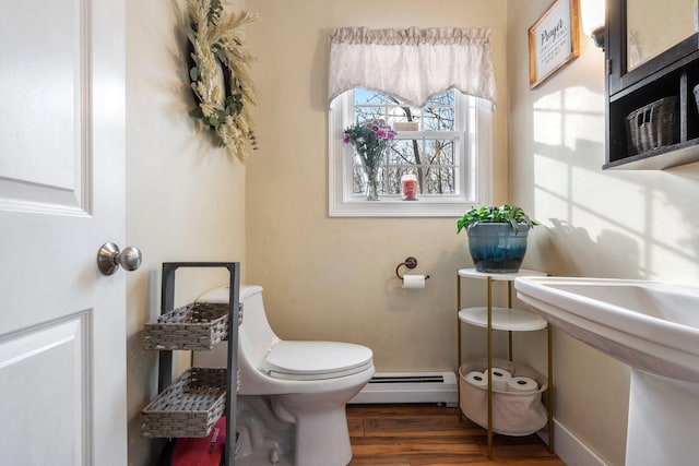 half bath featuring a baseboard heating unit, wood finished floors, and toilet