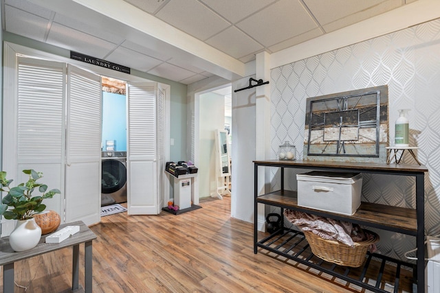 interior space with washer / clothes dryer, a drop ceiling, and wood finished floors