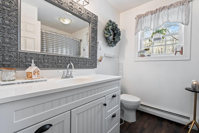 bathroom with toilet, a baseboard heating unit, wood finished floors, and vanity