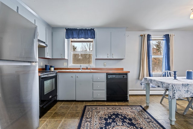 kitchen featuring butcher block countertops, baseboard heating, under cabinet range hood, and black appliances