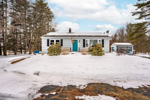 view of front of home featuring a chimney, a storage unit, and an outbuilding