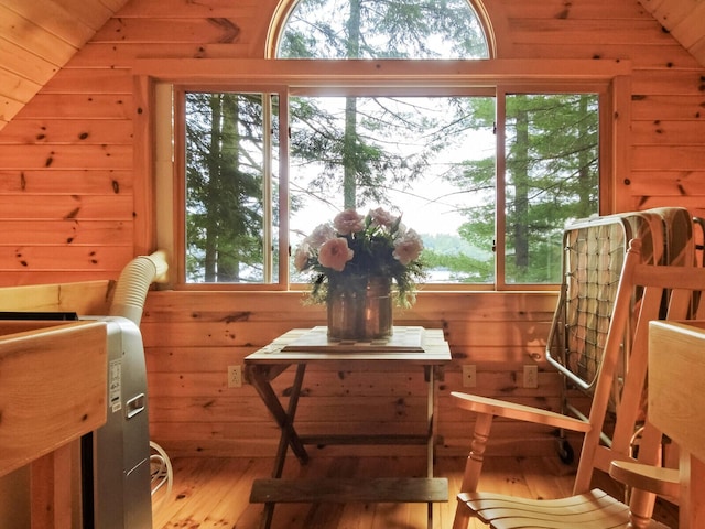 interior space featuring vaulted ceiling, wood finished floors, and wooden walls