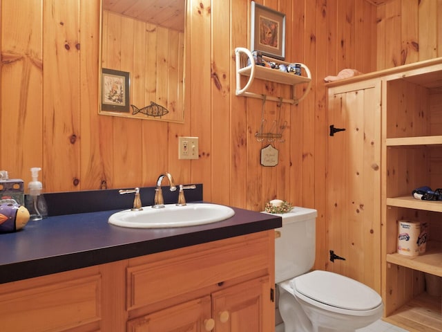 half bath with wood walls, vanity, and toilet