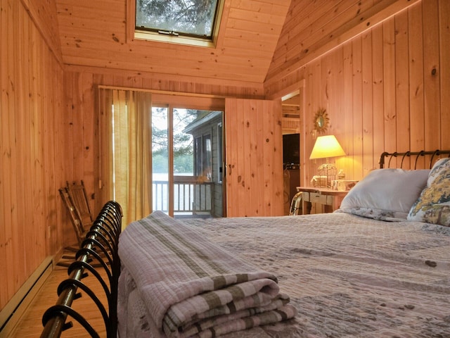 bedroom with vaulted ceiling with skylight, wooden walls, wood finished floors, access to exterior, and baseboard heating