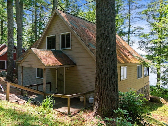 view of side of home featuring a shingled roof and a wooden deck