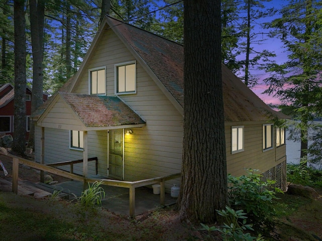 property exterior at dusk featuring roof with shingles