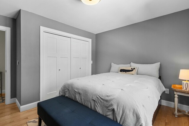 bedroom with a closet, baseboards, and light wood finished floors