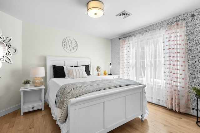 bedroom featuring light wood-style flooring, visible vents, and baseboards