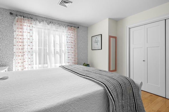 bedroom featuring a closet, visible vents, and wood finished floors