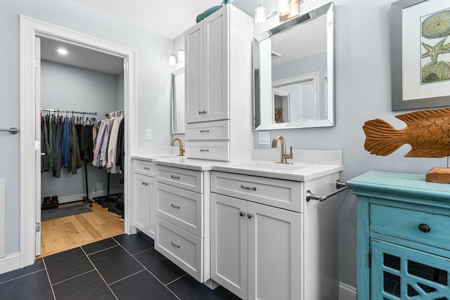 bathroom featuring tile patterned flooring, a walk in closet, and vanity