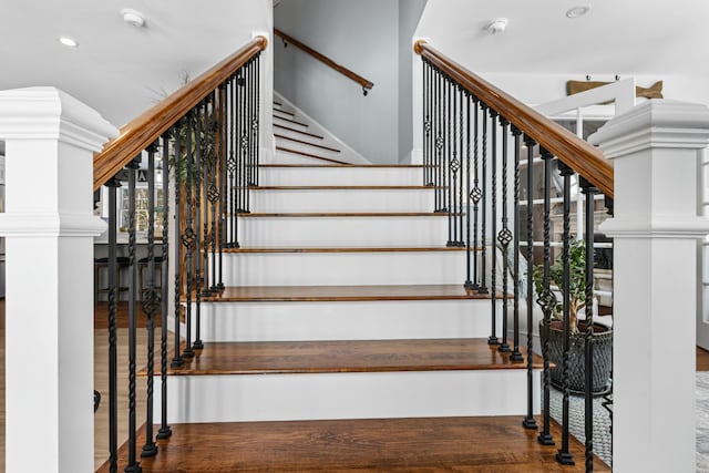 staircase featuring ornate columns, wood finished floors, and recessed lighting