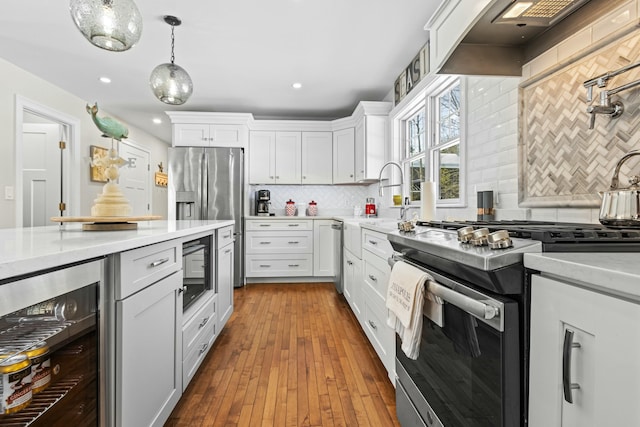 kitchen with wine cooler, custom range hood, appliances with stainless steel finishes, white cabinetry, and light stone countertops