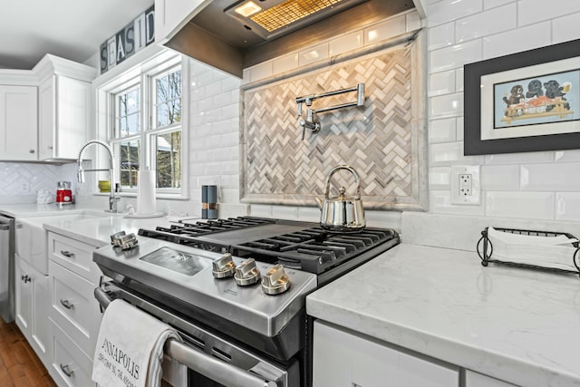 kitchen featuring backsplash, white cabinetry, wall chimney range hood, and light stone countertops