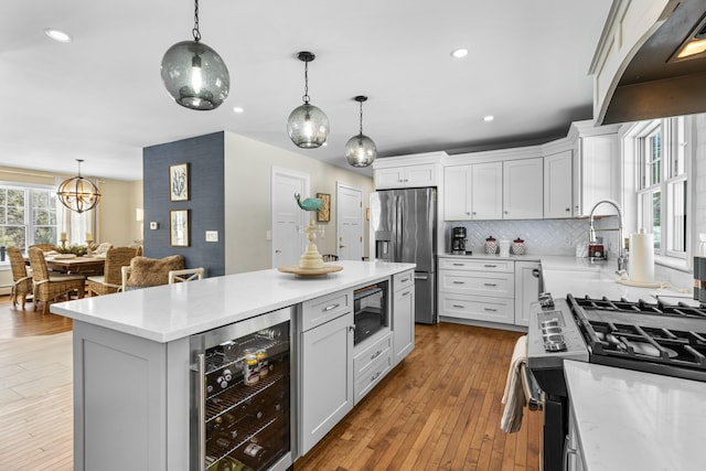 kitchen with beverage cooler, stainless steel appliances, pendant lighting, and white cabinets