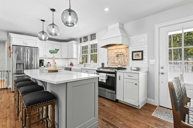 kitchen with stainless steel appliances, light countertops, custom range hood, and white cabinetry