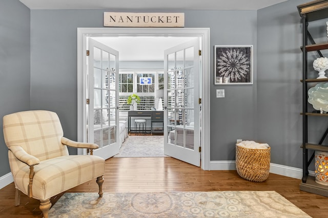 sitting room featuring french doors, baseboards, and wood finished floors