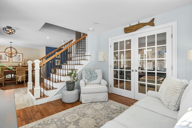 living area with stairs, french doors, wood finished floors, and a chandelier