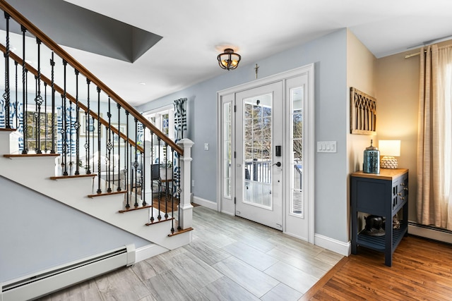 entryway with stairway, a baseboard radiator, wood finished floors, and baseboards