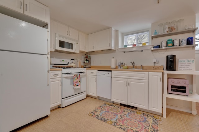 kitchen featuring white appliances, white cabinets, a sink, and light countertops