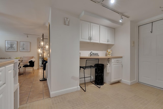 interior space with rail lighting, baseboards, white cabinetry, and light tile patterned flooring