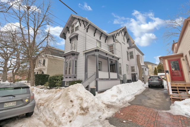 view of snowy exterior with covered porch and driveway