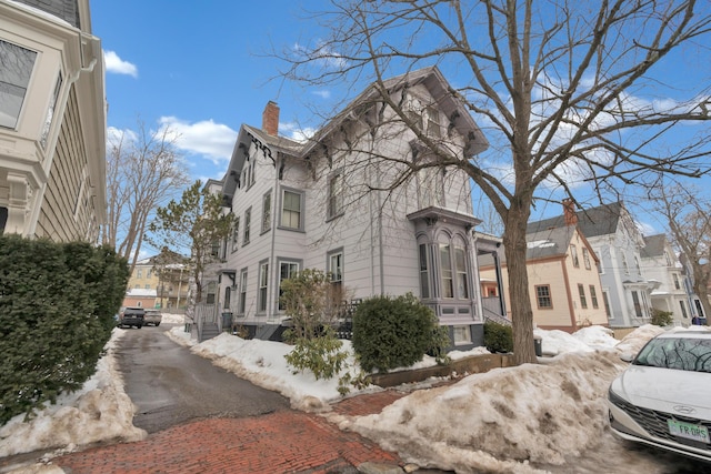 view of snowy exterior with a chimney and a residential view